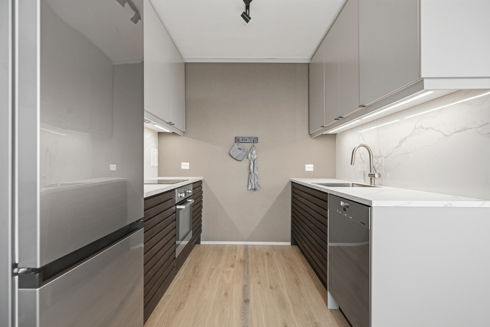 Fin nedfelt servant i stål. Stilige, marmorinspirerte plater mellom benk og overskap Galleribilde