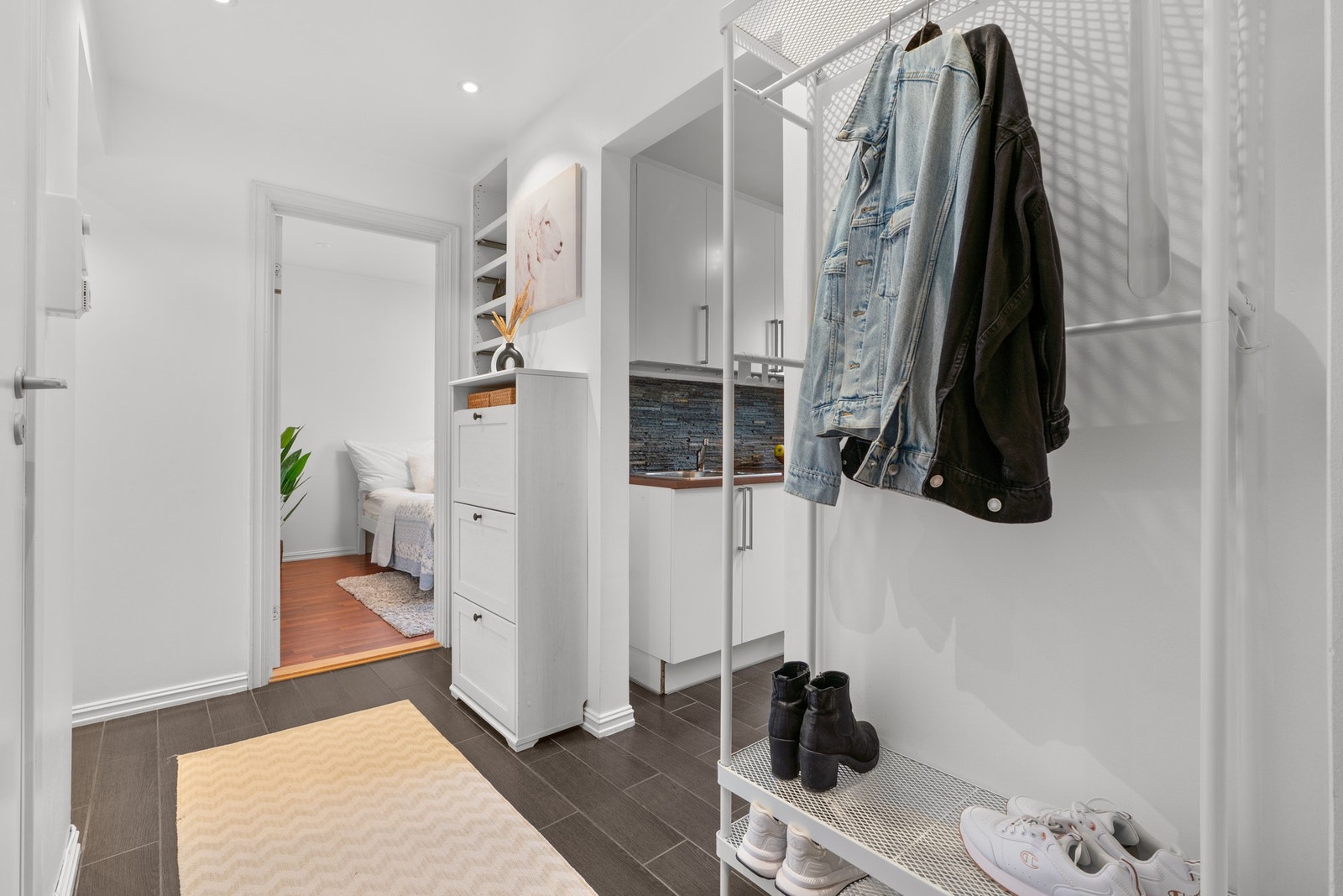 Inngangspartiet har et flislagt gulv og glatte, malte vegg- og himlingsflater som gir en enkel og ryddig overflate. Galleribilde