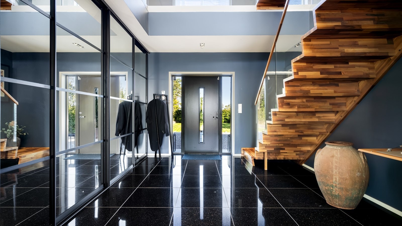 Romslig gang med flis på gulv og en enorm skyvedørsgarderobe Galleribilde