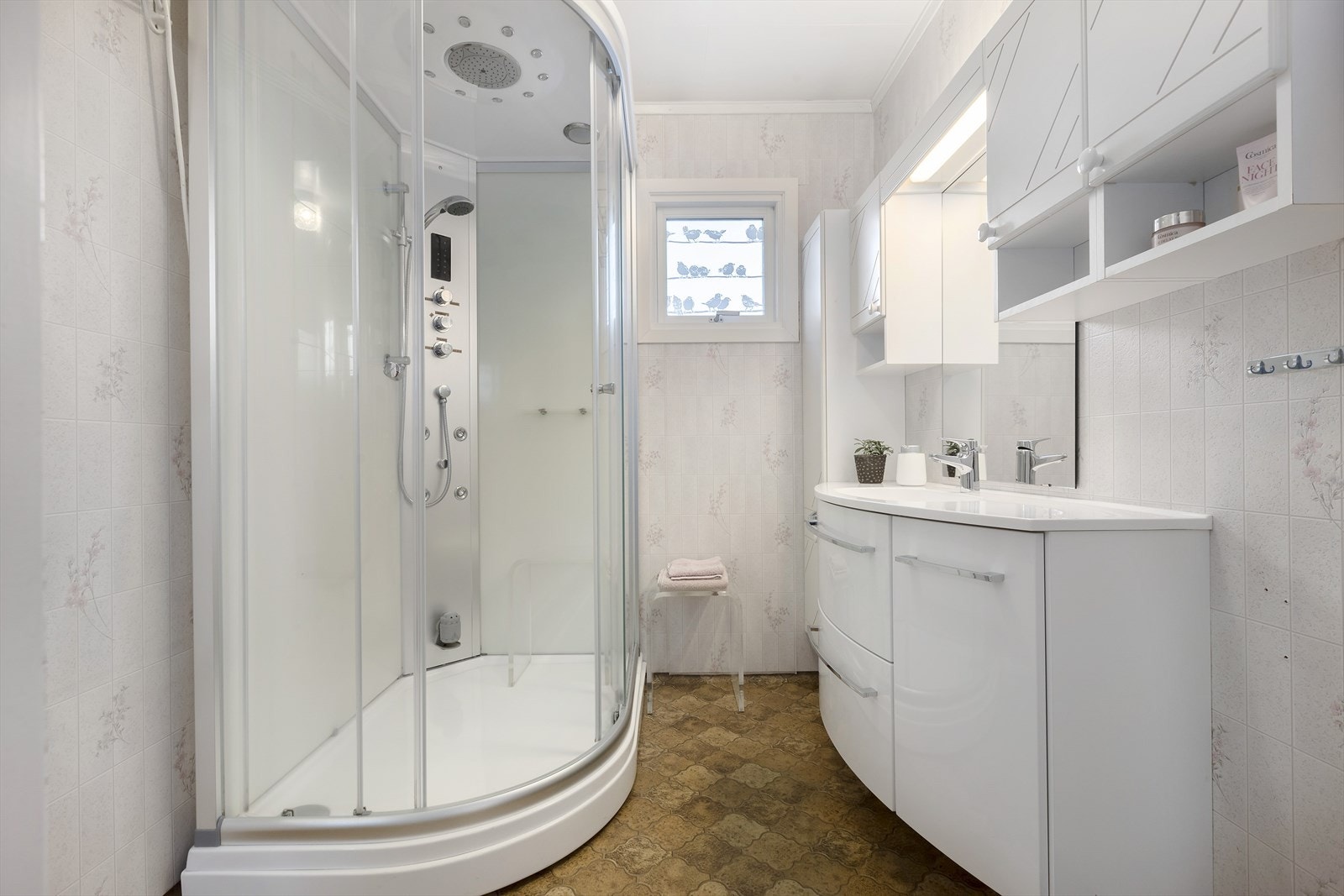 Bad med dusjkabinett og hvit innredning med slette fronter Galleribilde