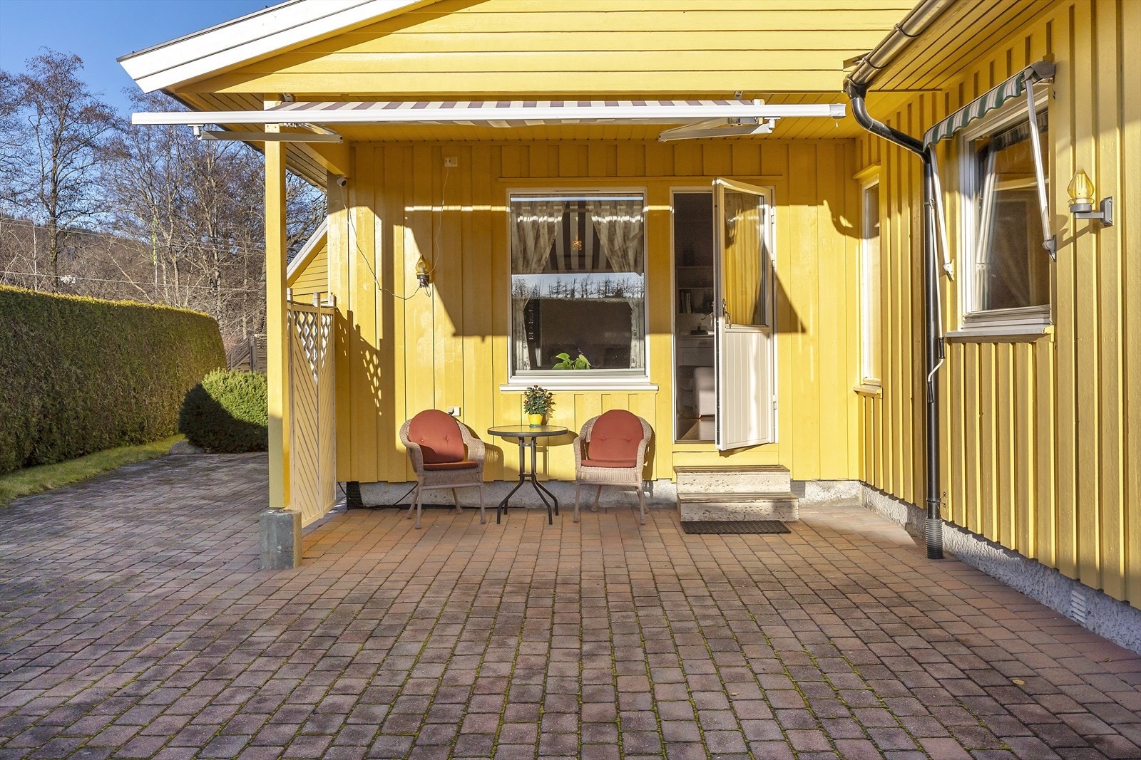 Delvis overbygget uteplass med markise og belegningsstein Galleribilde