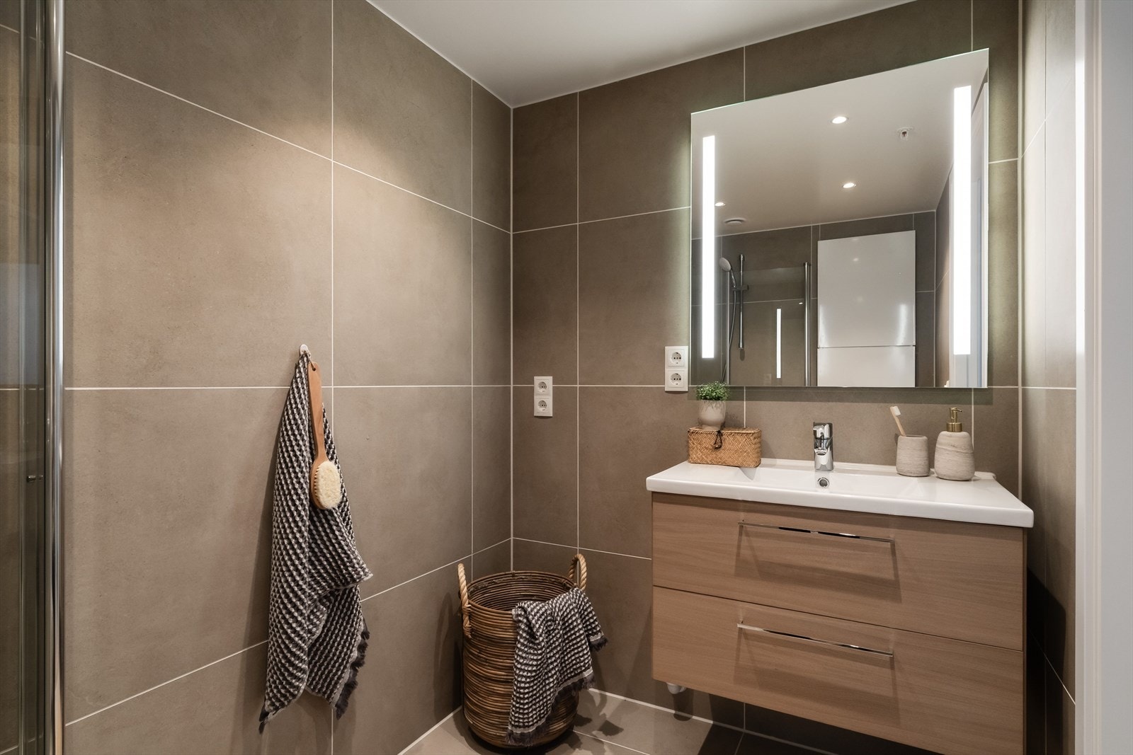 Badet er flislagt både på gulv og vegger. Her får du servant i underskap, speil med integrert belysning, dimmbare downlights og opplegg for vaskemaskin. Galleribilde