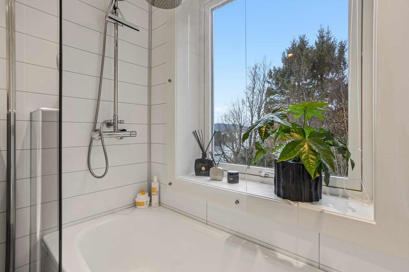 Stilrent og moderne bad med badekar, vegghengt toalett og god oppbevaringsplass. Uten innsyn og fin sjøutsikt fra badet. Galleribilde