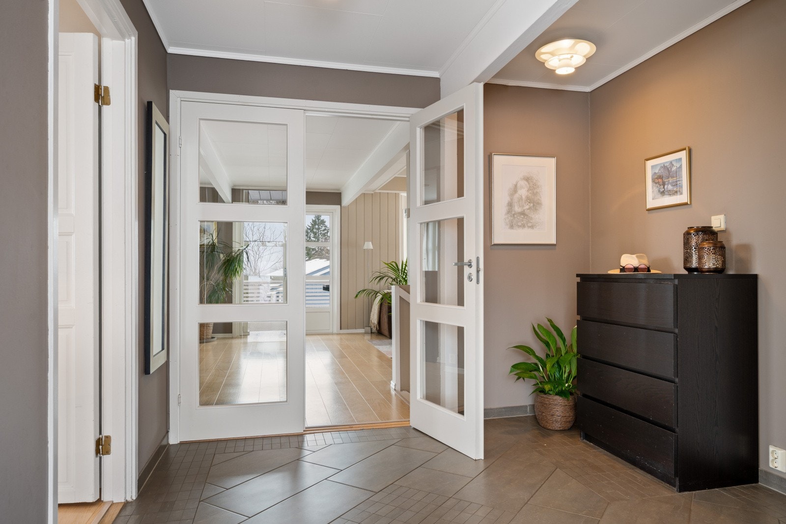 Fra hallen åpner doble glassdører inn mot boligens sosiale sone i første etasje. Galleribilde