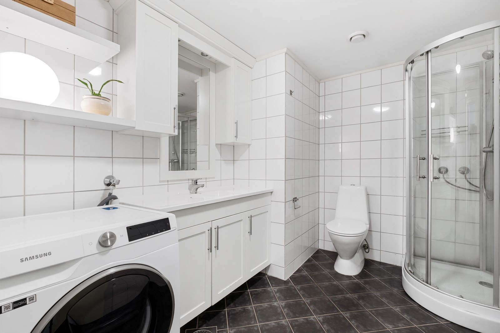 Badet er flislagt og utstyrt med dusjkabinett, toalett og servantinnredning. Galleribilde