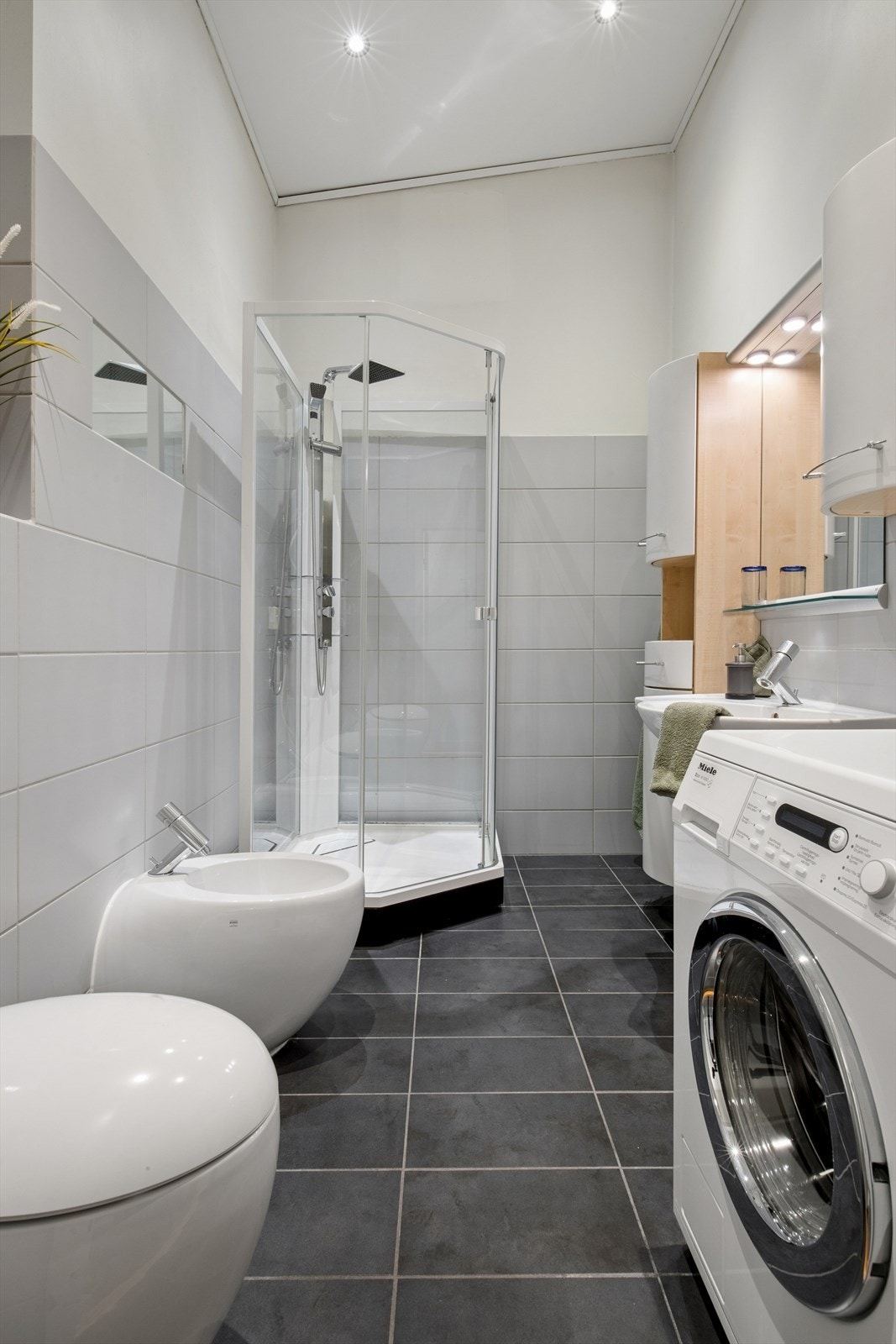 Badet ble renovert i 2004 og er stilrent innredet med store, grå fliser på gulvet og lyse fliser i kombinasjon med malte flater på vegg. I gulvet har man også varmekabler for ekstra komfort (se punkt "ferdigattest"). Galleribilde