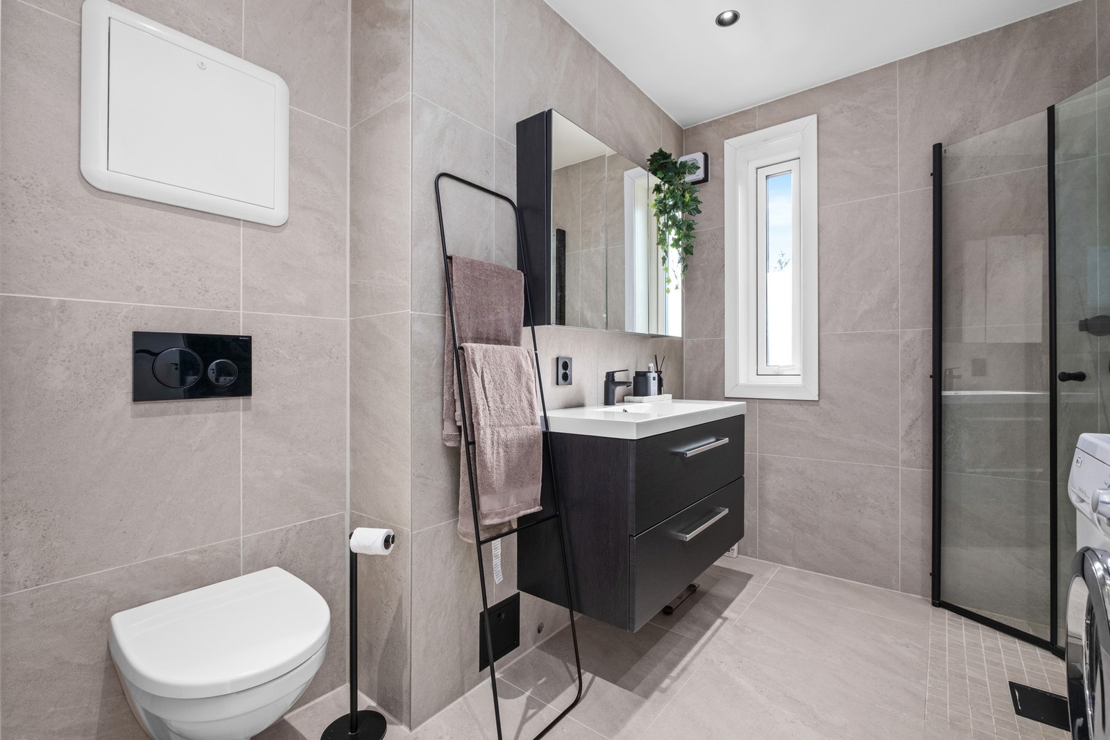 Meget pent flislagt baderom på 5,1 kvm. Her får du behagelig gulvvarme, vegghengt wc, dusjhjørne med innfellbare dører, lekker innredning med speilskap og opplegg til vaskemaskin. Galleribilde