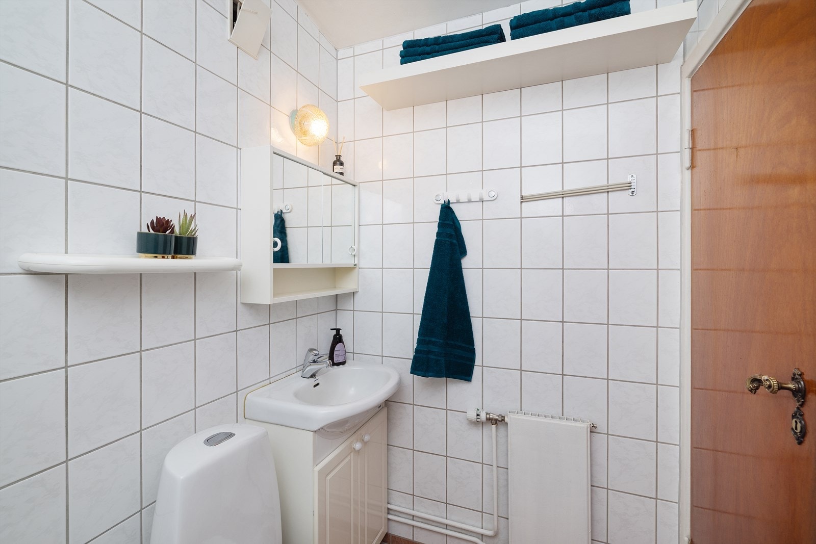 Flislagt bad med servantinnredning, speil og toalett. Rommet varmes opp med radiator. Galleribilde