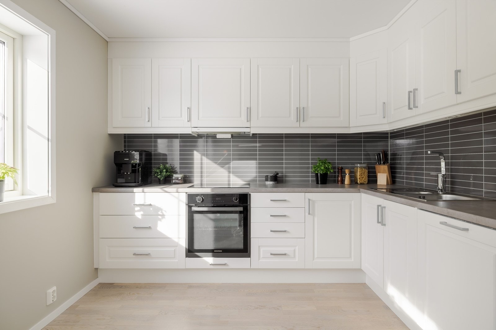 Laminerte benkeplater med nedfelt oppvaskkum i rustfritt stål. I benkeryggen er det kitchenboards. Galleribilde