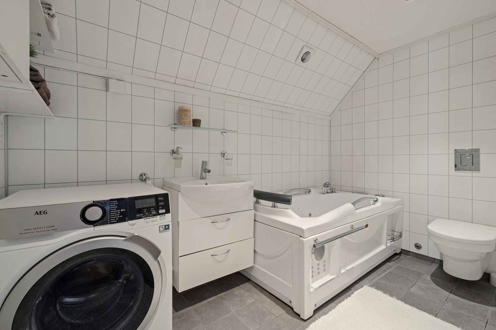 Baderom har opplegg for vaskemaskin, servant med underskap, boble badekar og vegg hengt toalett. Varmekabler i gulv. Galleribilde