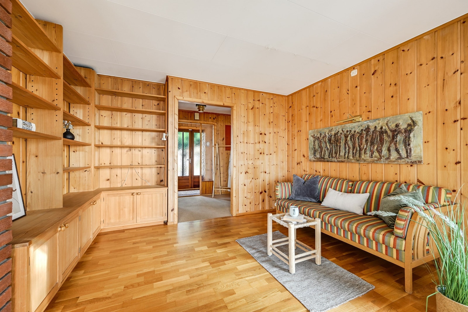 Stue med lun og varm atmosfære, preget av flotte trepaneler og gode oppbevaringsløsninger i innebygde hyller. Galleribilde