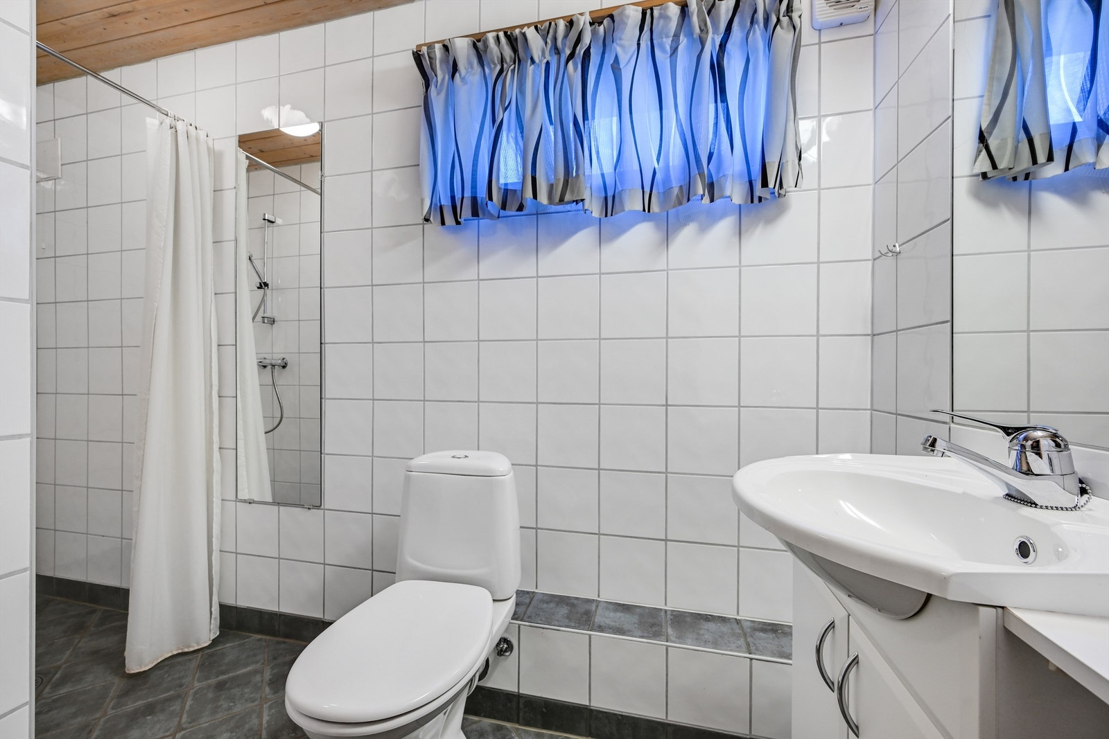 Lyst og praktisk baderom med flislagte overflater og god plass rundt både dusj og innredning. Galleribilde