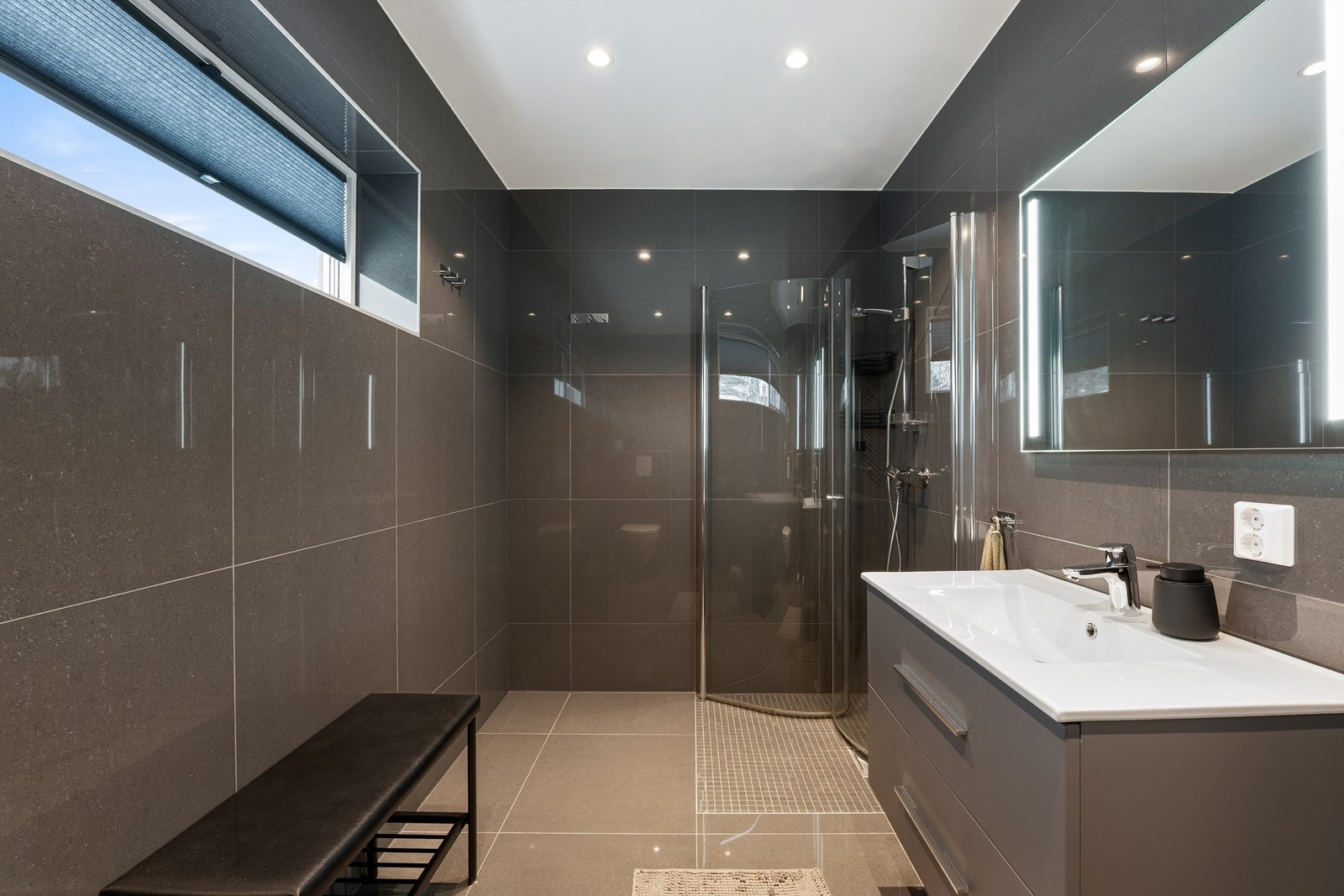 Like fliser og innredninger skaper helhet og en rød tråd mellom boligens to lekre bad. Dette er størst og på romslige 6 kvm. Galleribilde