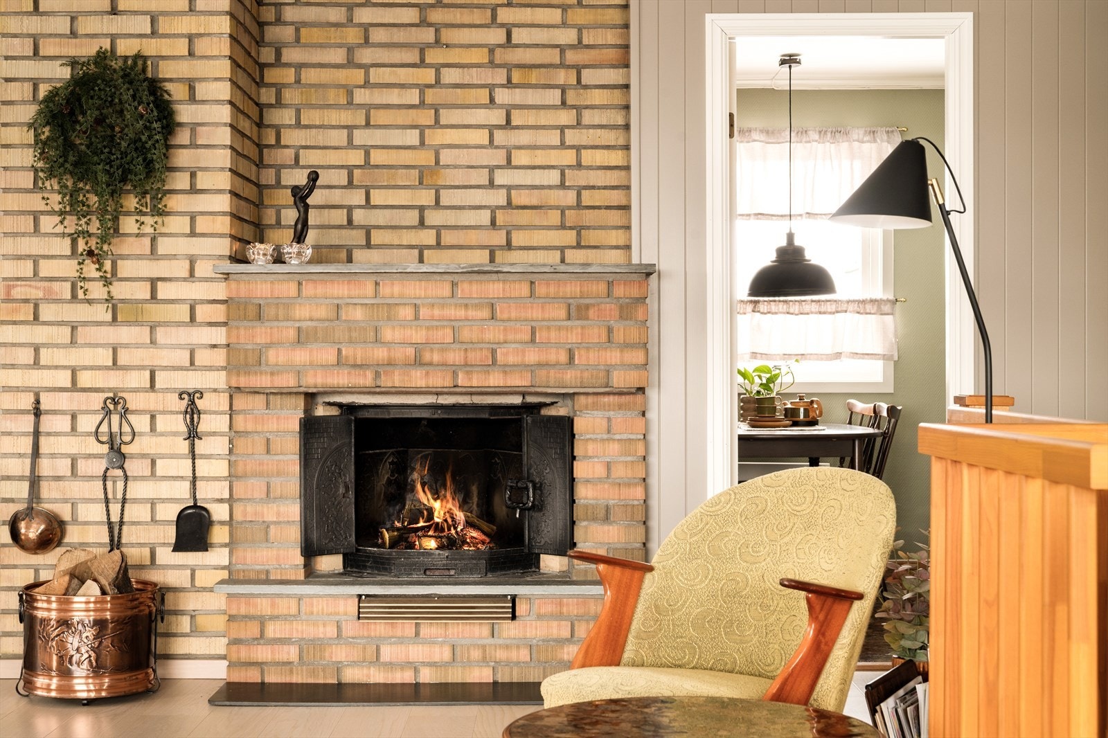 De solide teglsteinene gir rommet tyngde og karakter, med sin lune fargetone og levende overflate. Den rustikke fasaden binder rommene sammen på en lun og karakterfull måte, og skaper en rød tråd mellom kjøkkenets mørke tretoner og stuens lysere uttrykk. Galleribilde