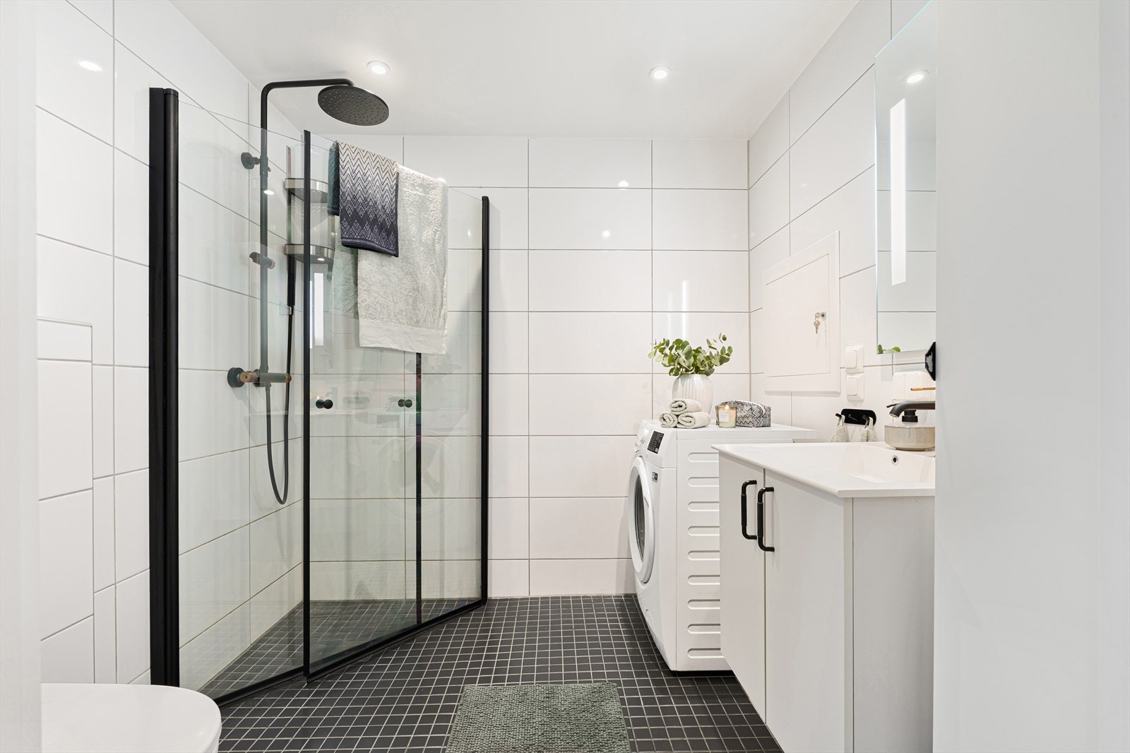 Det 4 m² store badet fremstår som innbydende med helflisede overflater, behagelig gulvvarme, downlights i tak og er oppgradert med svarte detaljer. Galleribilde