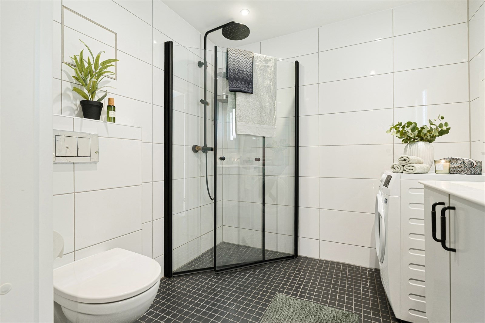 Badet er utstyrt med innfellbare dusjdører, mekanisk avtrekk, toalett, servant i skap, og opplegg for vaskemaskin/tørketrommel. Galleribilde