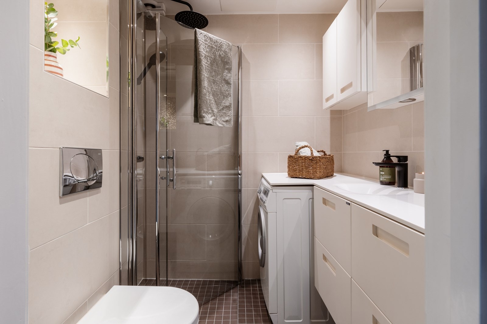 Videre er rommet utstyrt med vegghengt toalett med innebygd sisterne, dusjsone med innfelte dusjdører i herdet glass og benkeplate i corian. Galleribilde