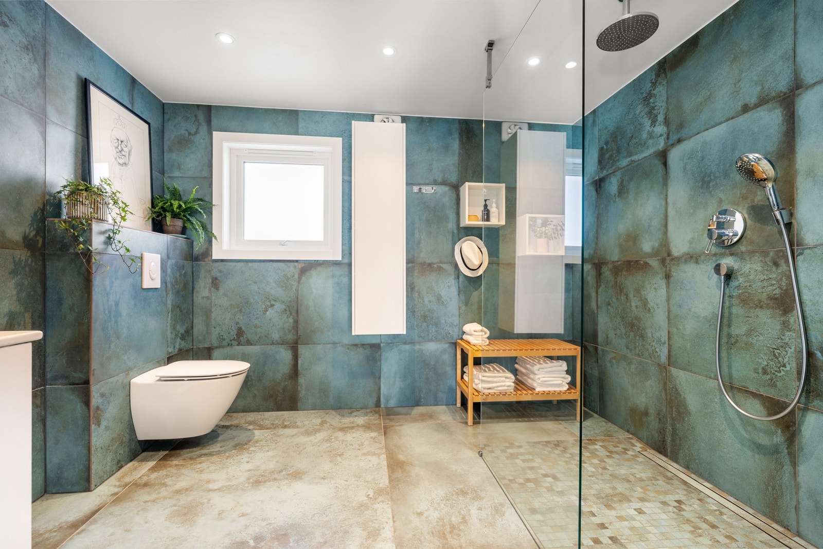 Badet fremstår romslig og gjennomført med store fliser, praktiske nisjer og gode oppbevaringsløsninger. Galleribilde