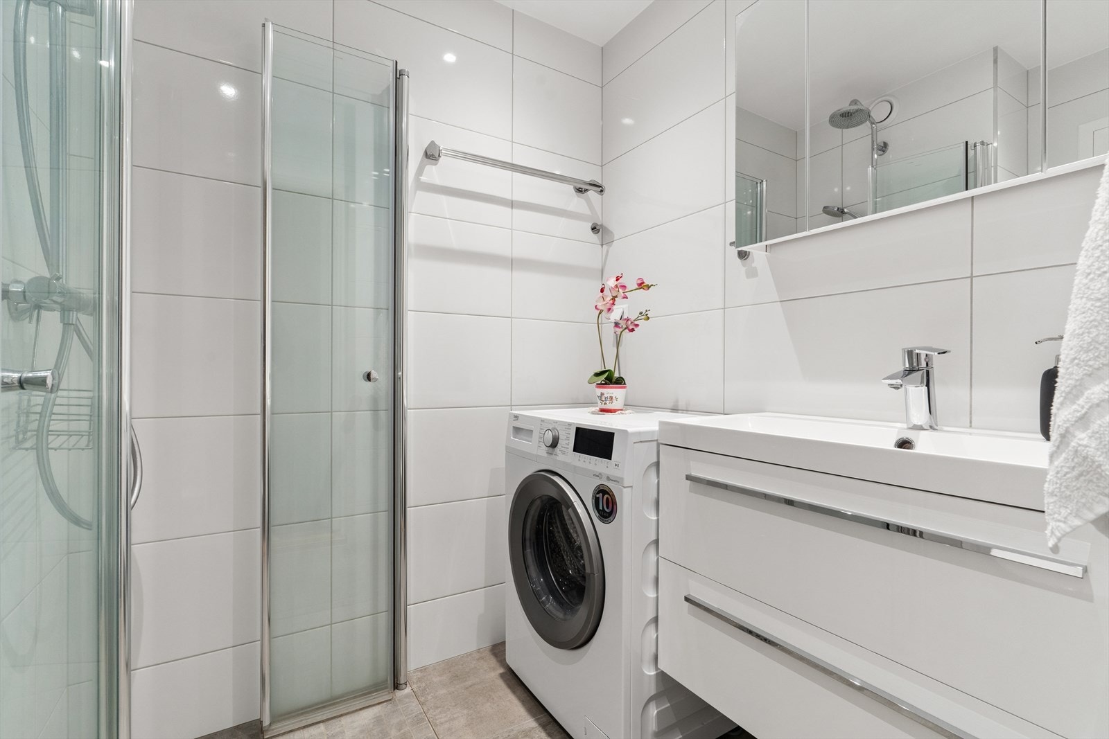 Badet har innredning med nedfelt servant, veggmontert toalett, dusjvegger/hjørne og opplegg for vaskemaskin. Vaskemaskin medfølger. Galleribilde