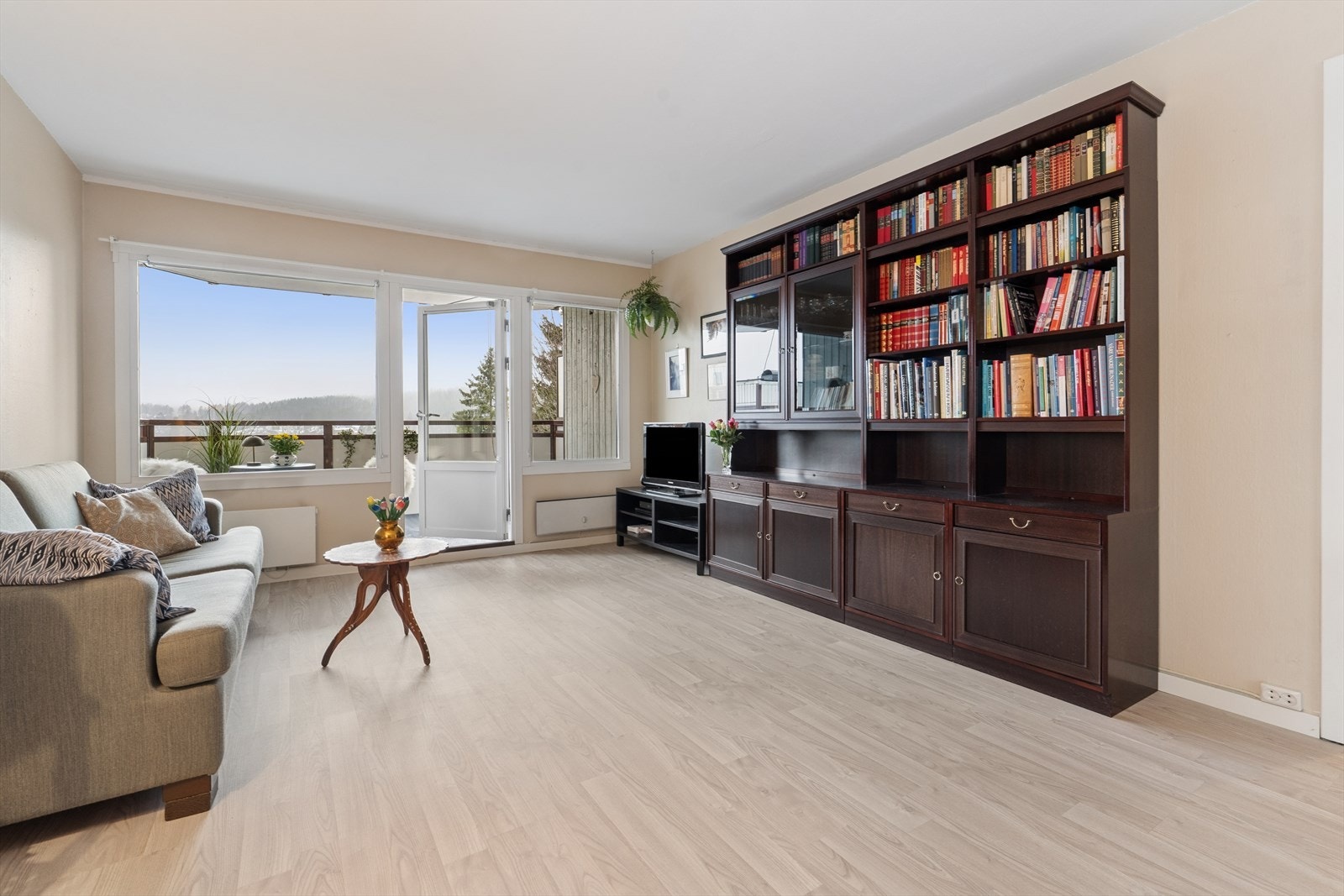 Store vindusflater og balkongdør slipper inn rikelig med naturlig lys og gir stuen en lys og luftig atmosfære. Galleribilde