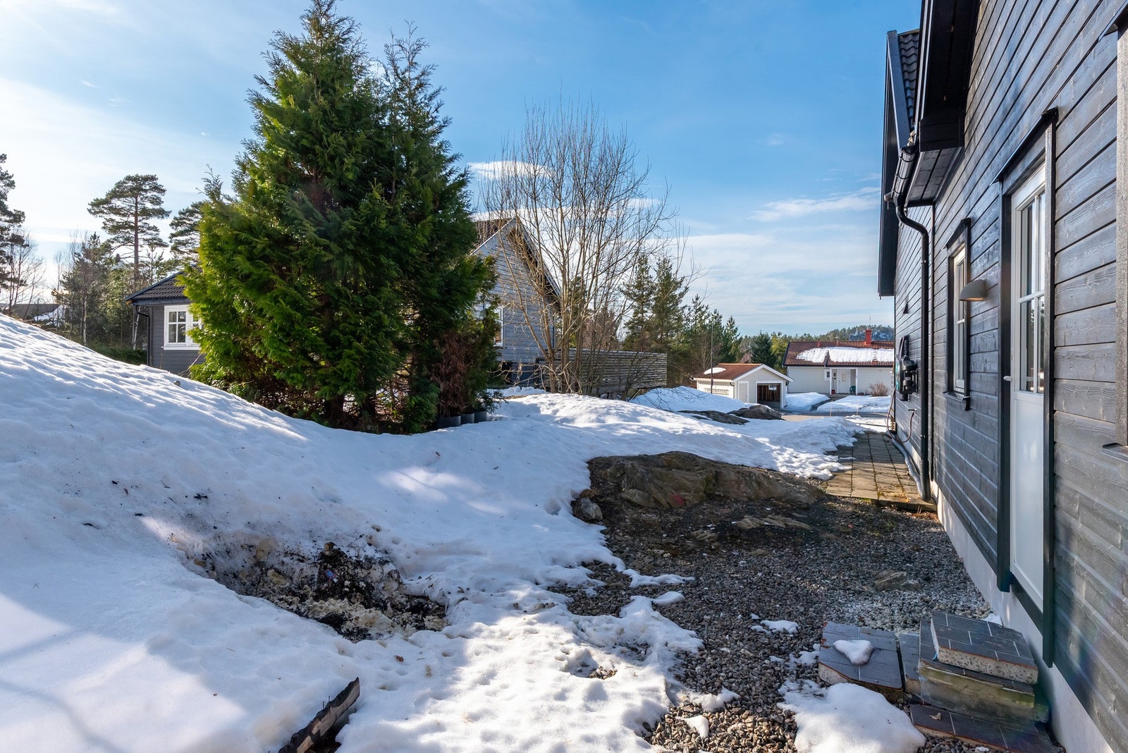 Uteplass ved siden av boligen med direkte utgang fra vaskerom; et spennende område med potensial for en innbydende sone. Galleribilde