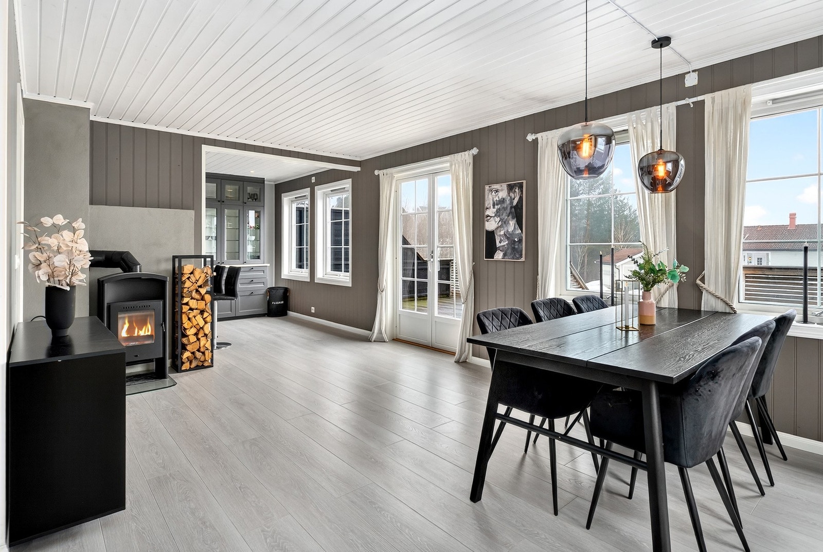 Lys og trivelig spisestue med peisovn, glimt av kjøkkenet og utgang til terrasse for hyggelige måltider ute og inne. Galleribilde