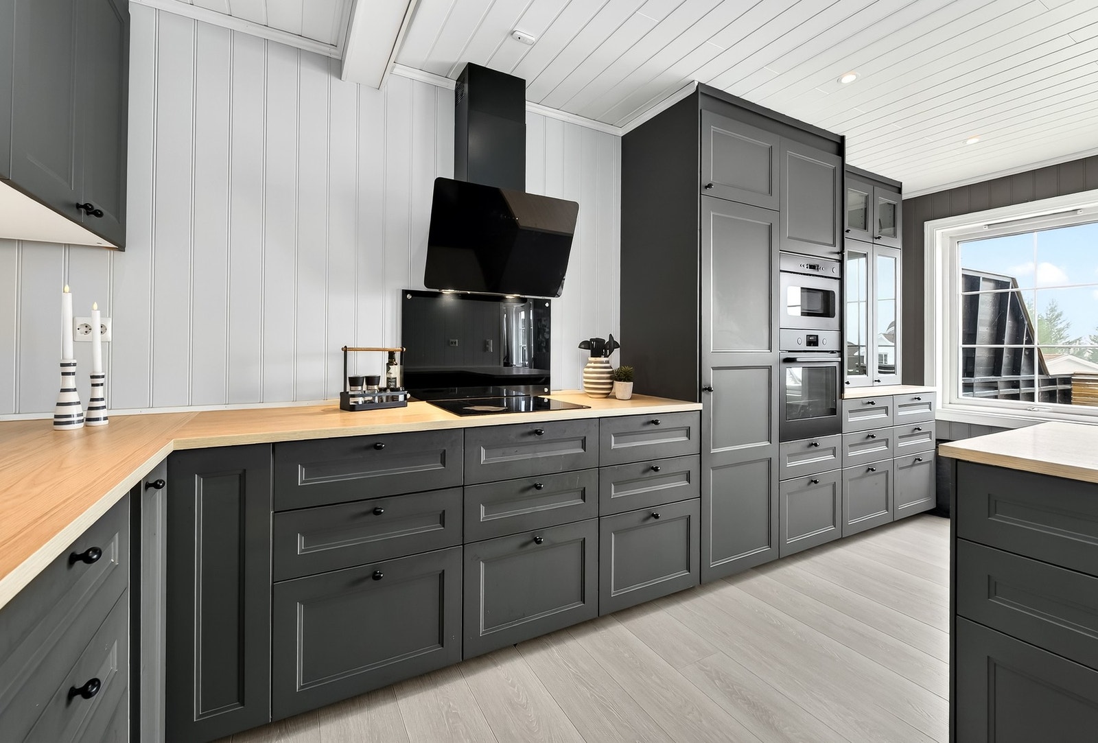 Praktisk kjøkken med gjennomtenkt planløsning, grå innredning og rikelig lagringsplass. Naturlig lys skaper en lys og innbydende atmosfære. Galleribilde