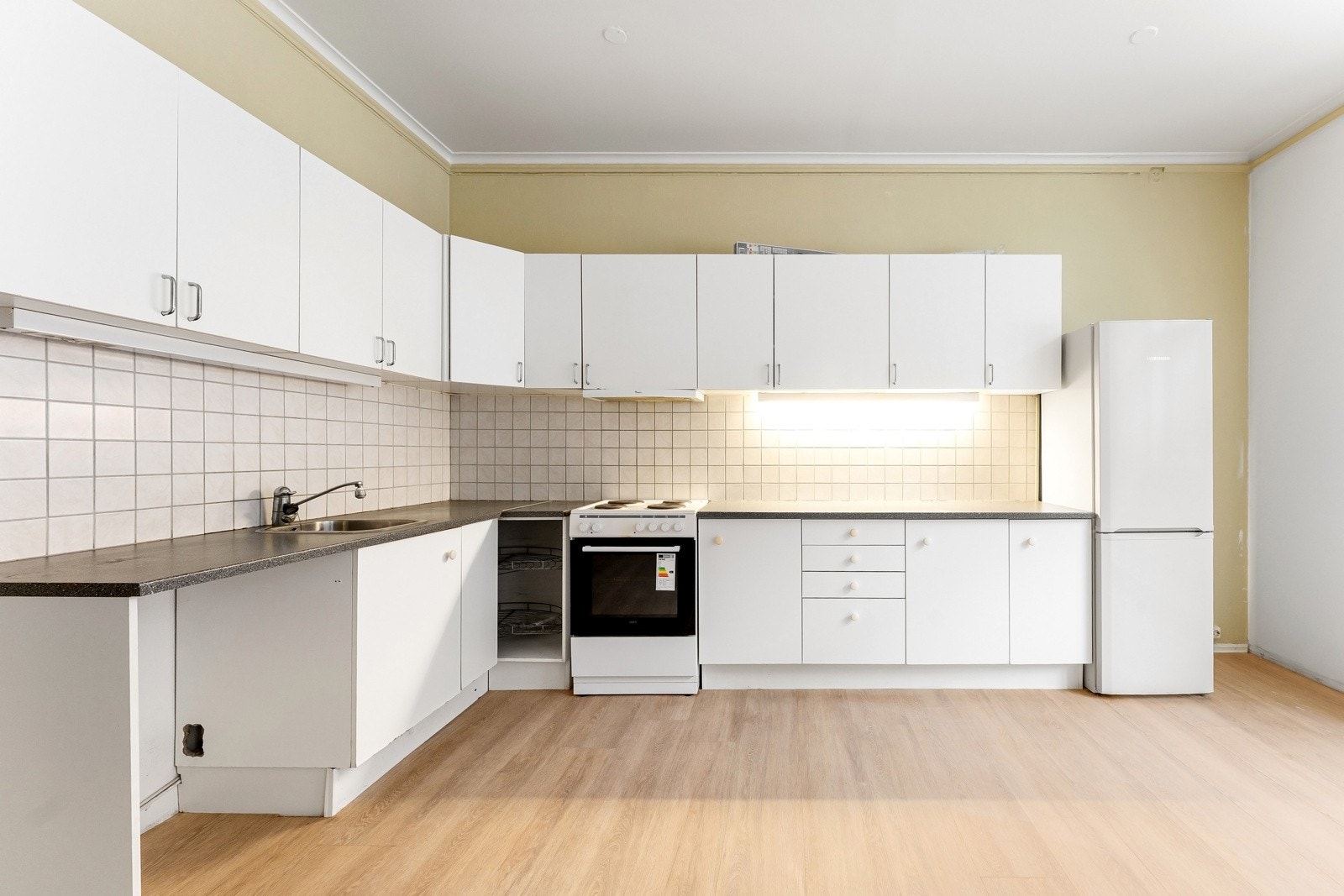 Eldre kjøkkeninnredning med plass til hvitevarer samt opplegg til vaskemaskin Galleribilde