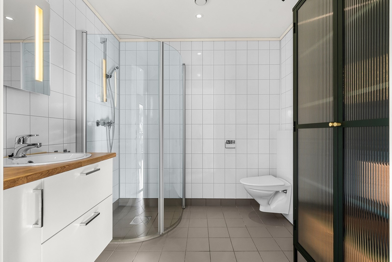 Bad 2.etg.Flis på gulv og våtromsplater på vegger. Malt overflate i himling. Gulvvarme. Utstyrt med innfellbare dusjdører, veggmontert wc, servantskap og mekanisk avtrekk. Galleribilde