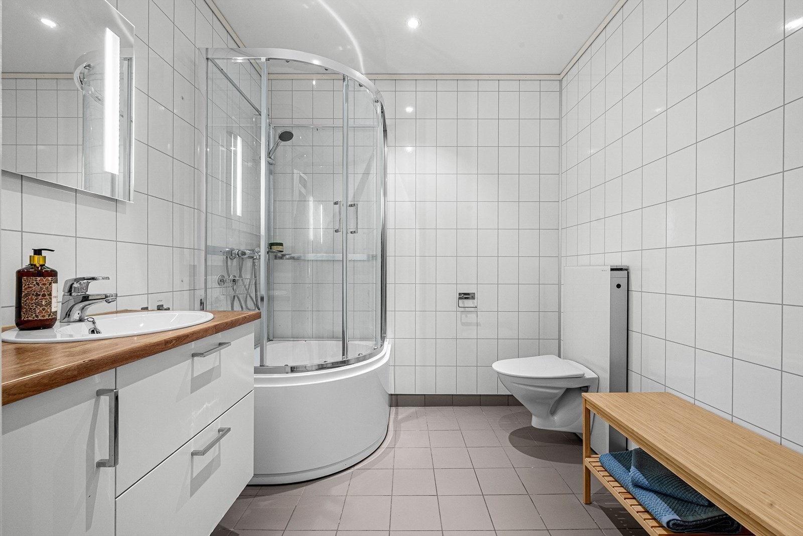 Flis på gulv og våtromsplater på vegger. Malt overflate i himling. Gulvvarme. Utstyrt med dusjkabinett, servantskap, veggmontert wc og mekanisk avtrekk. Galleribilde