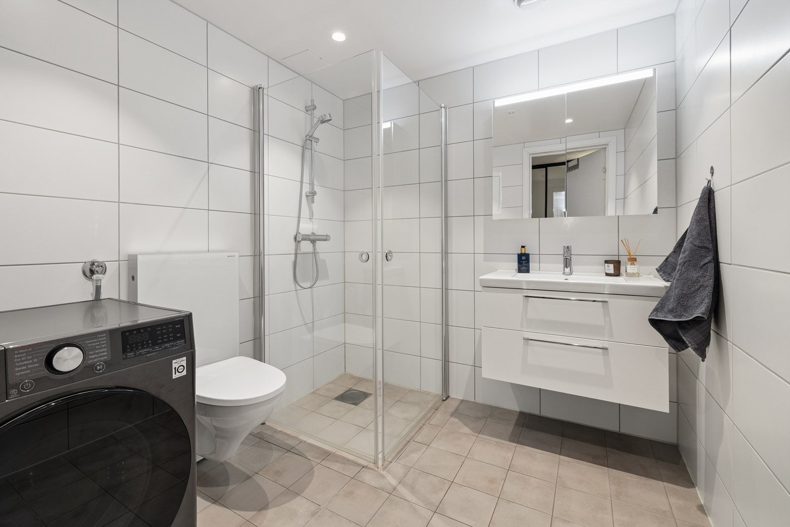 Varmekabler i gulv, dusj på vegg og servant med over-underskap for oppbevaring. Galleribilde