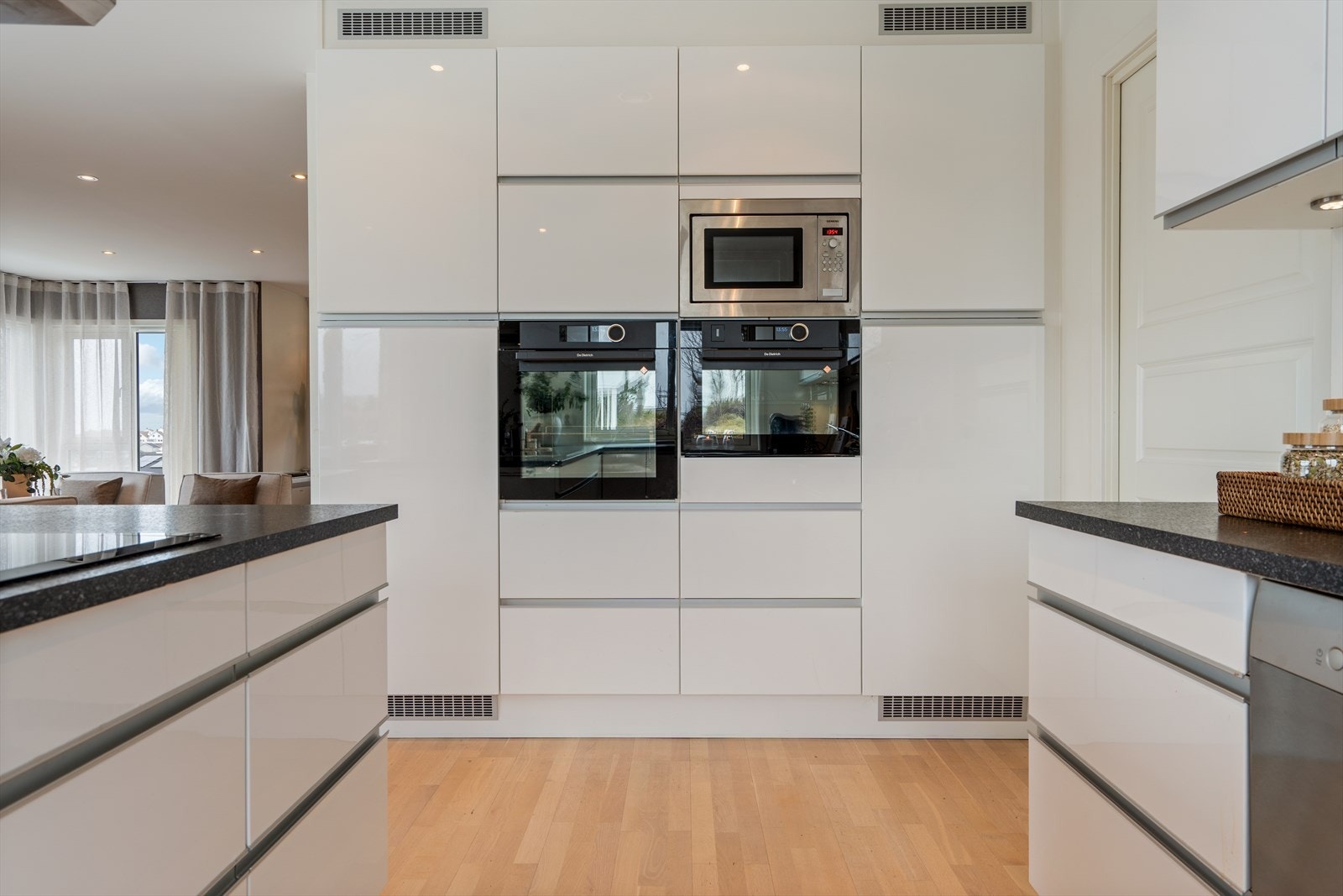 Pent kjøkken fra Designa med hvite, slette fronter. God skap- og benkplass. Det er integrert oppvaskmaskin, kjøleskap, induksjonstopp, kombi/damp og stekeovn. Galleribilde