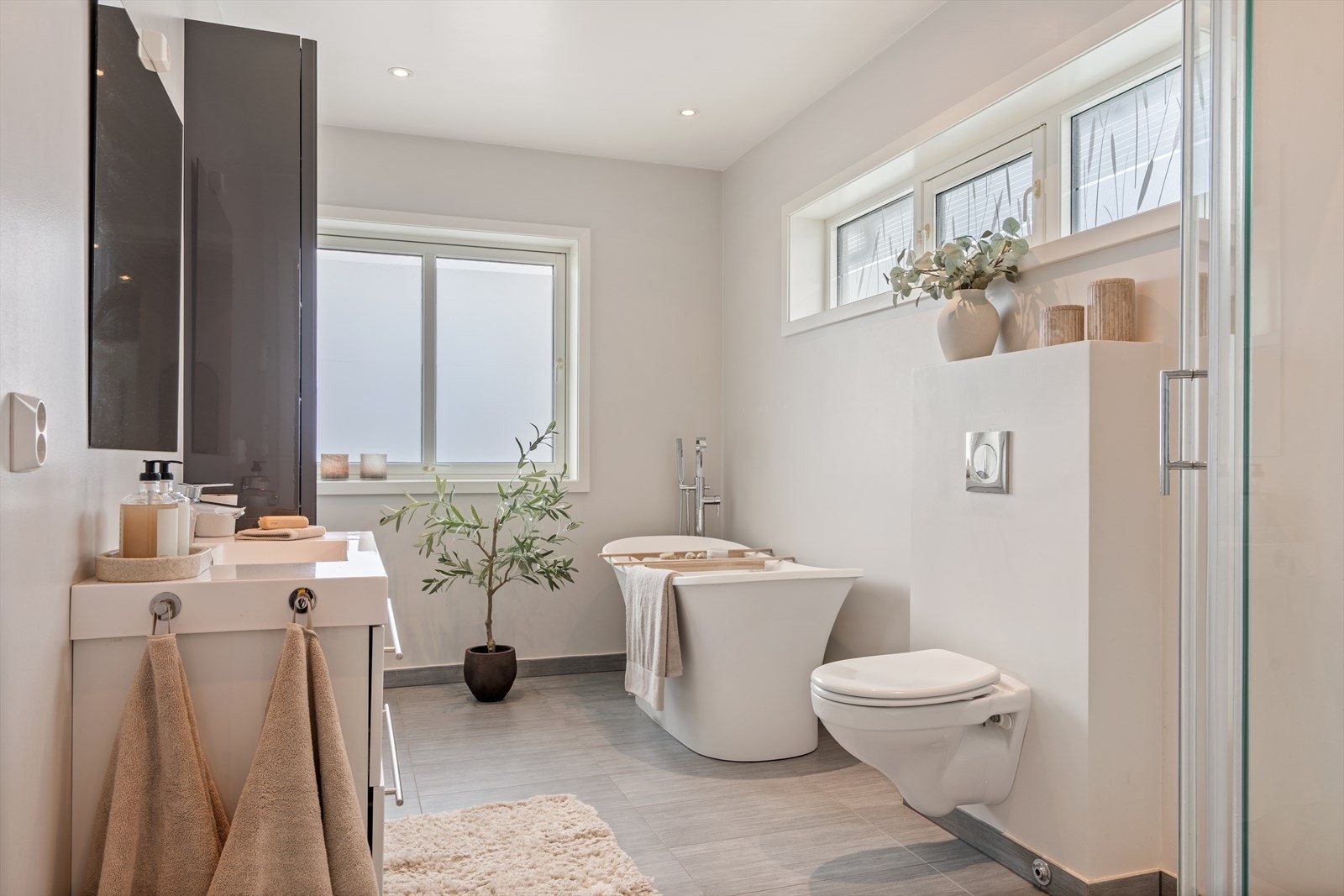 Flislagte baderom i begge etasjer med dusjnisje, badekar, vegghengt toalett og servant med skuffeseksjon. Galleribilde