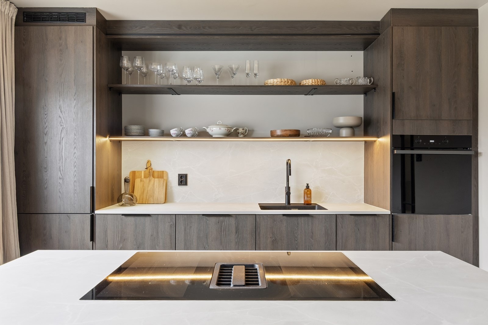 Kjøkkenventilator med kullfilter er elegant integrert i platetoppen på kjøkkenøya. Galleribilde