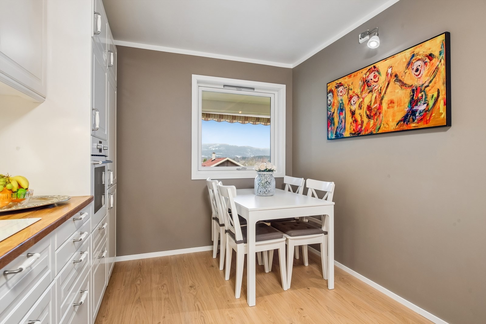 Fra spiseplassen på kjøkkenet har man utsikt over nærområdet gjennom et 2-lags trevindu. Galleribilde