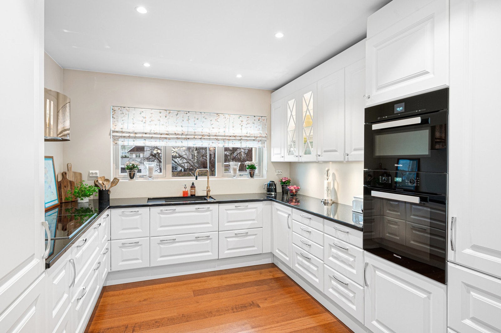 Kjøkkeninnredning har profilerte fronter med integrert kjøleskap, stekeovn, kombiovn og oppvaskmaskin. Benkeplate i steinmateriale, med nedfelt induksjonstopp Galleribilde