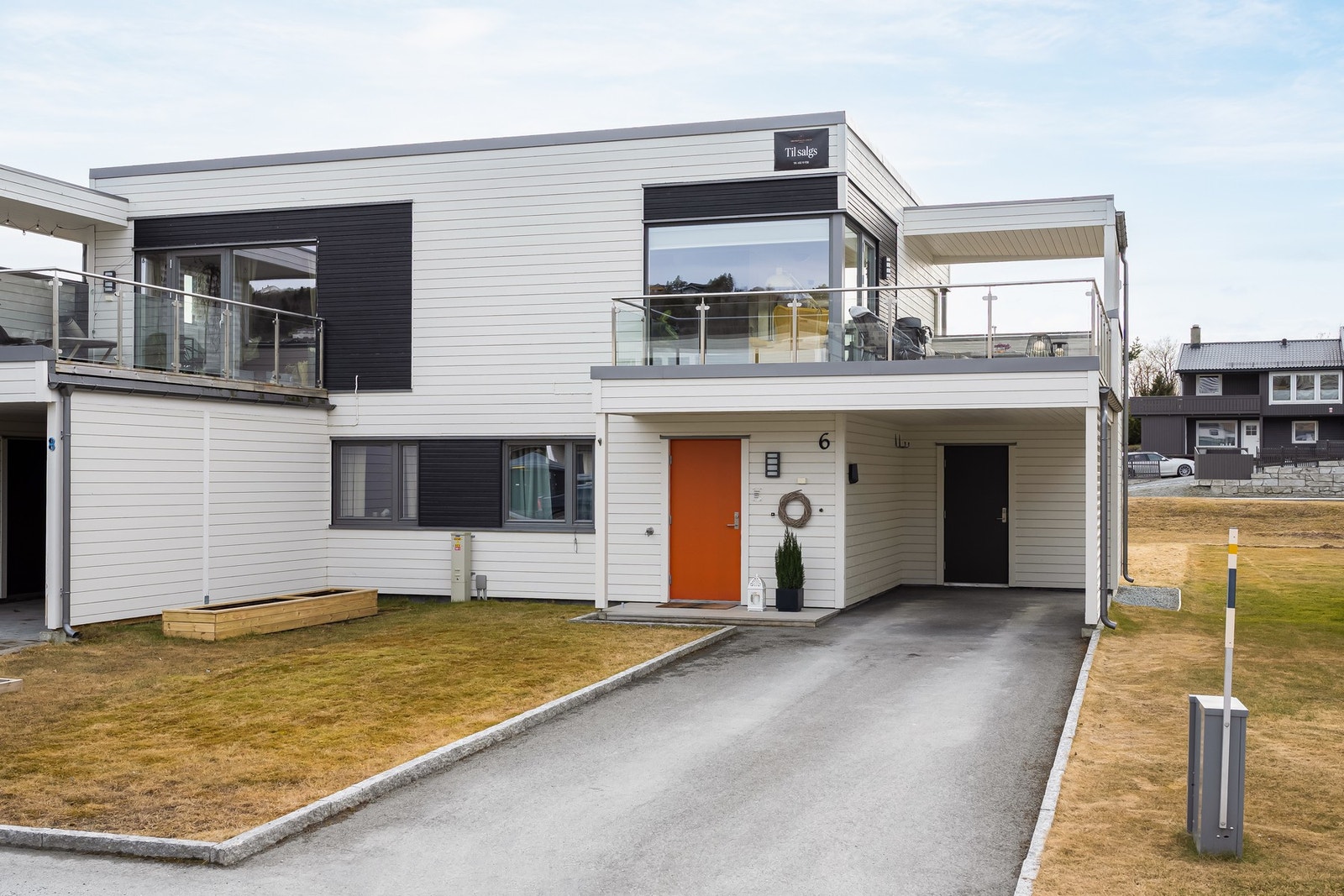 Asfaltert gårdsplass og carport med elbil-lader. Galleribilde