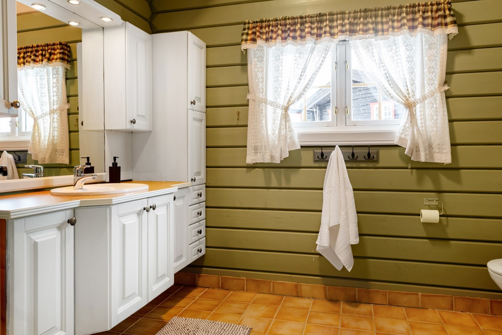 Hytta har gode fasiliteter for velvære med sine to bad/vaskerom. Begge rommene har baderomsinnredning i heltre med profilerte fronter i over-og underskap og speil med belysning. Galleribilde