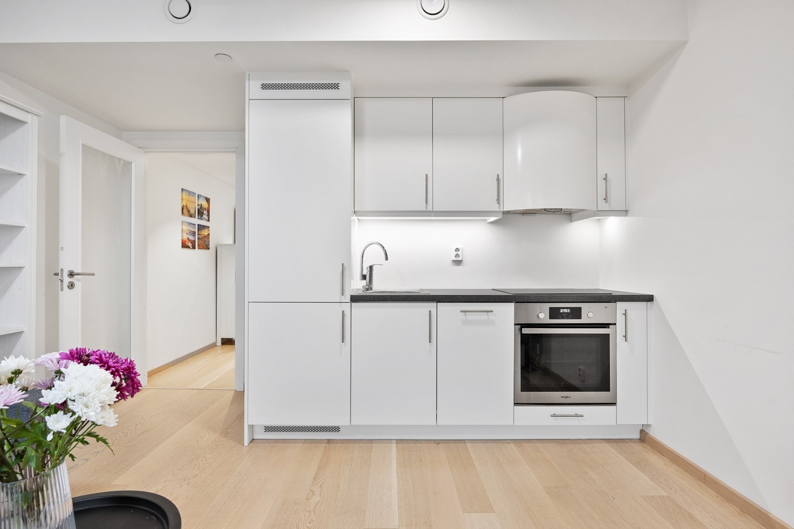 Kjøkkenet har hvitmalte glatte fronter, laminat benkeplate og integrerte hvitevarer. Galleribilde