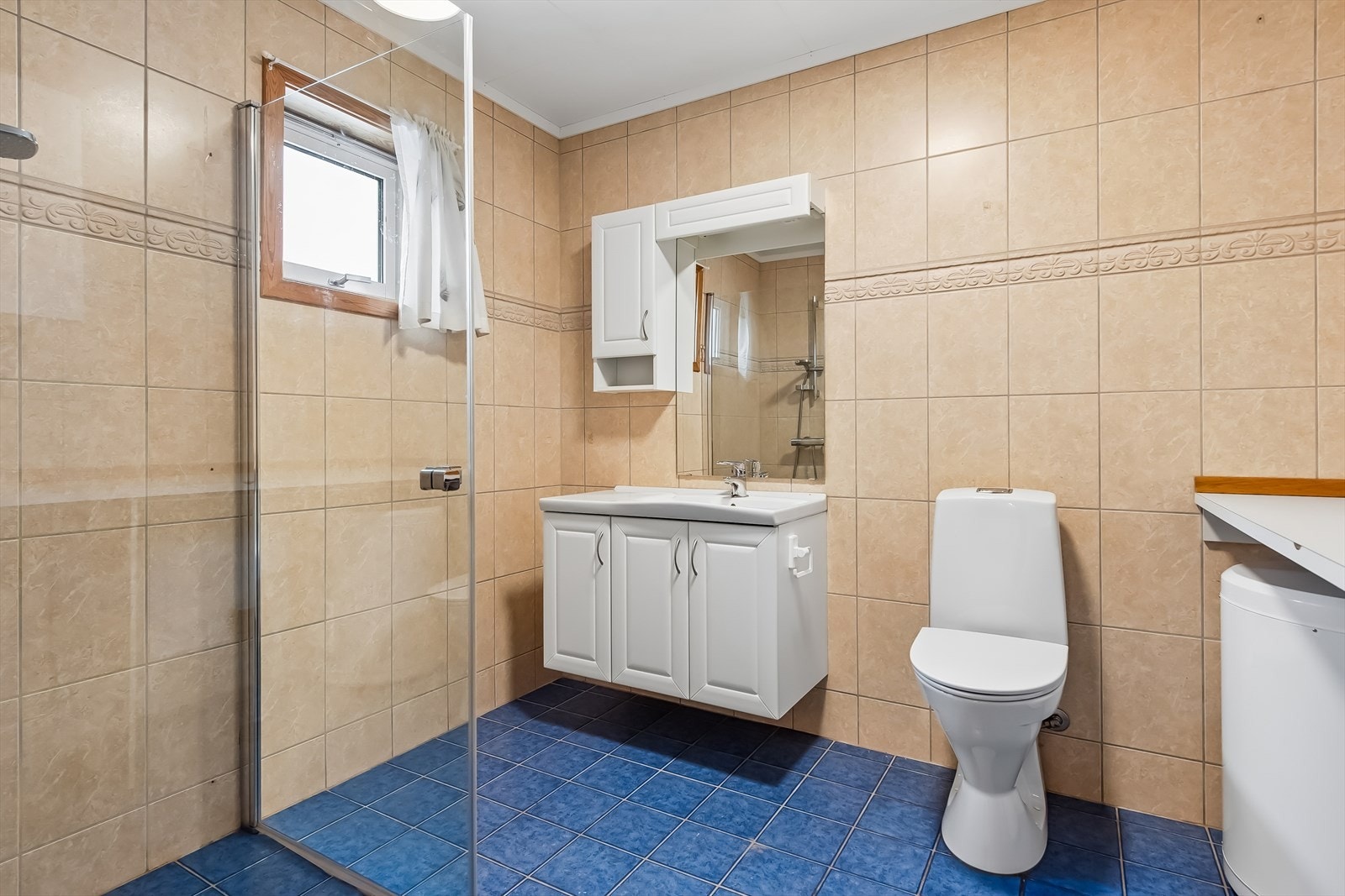 Flislagt bad fra byggeåret med servantinnredning, toalett og dusjhjørne. Galleribilde