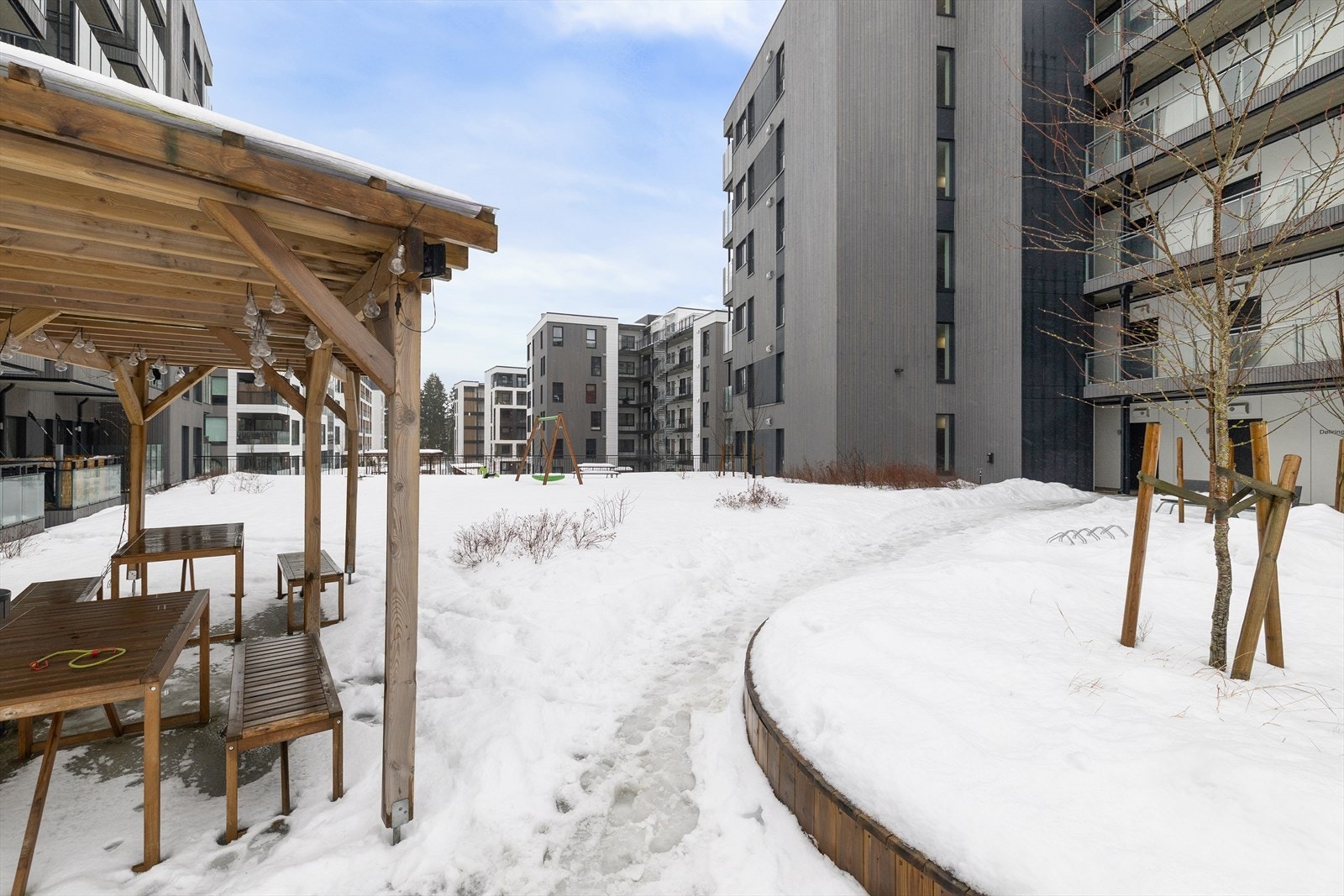 Fint fellesarealer på sameiets tomt med sittegrupper, pergola, internveier, beplantning og lekeareal. Galleribilde