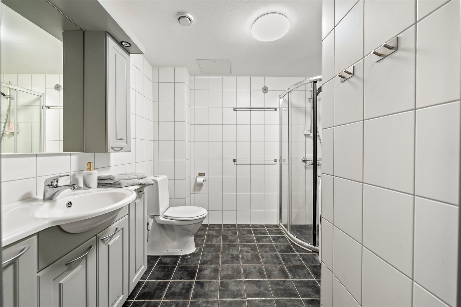 Pent og funksjonelt baderom med flislagte overflater. Galleribilde