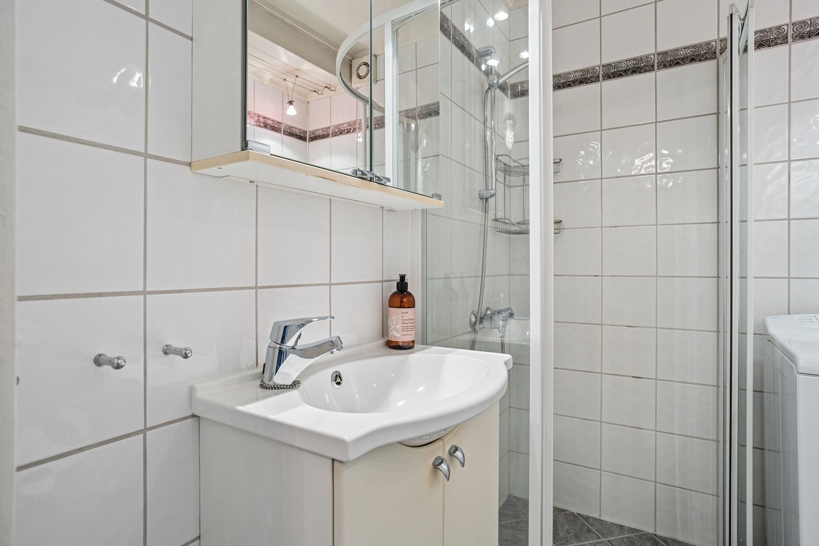 Innredning med servant med skap, speil med oppbevaring og dusjhjørne. Rommet har mekanisk avtrekk som sikrer god ventilasjon. Galleribilde