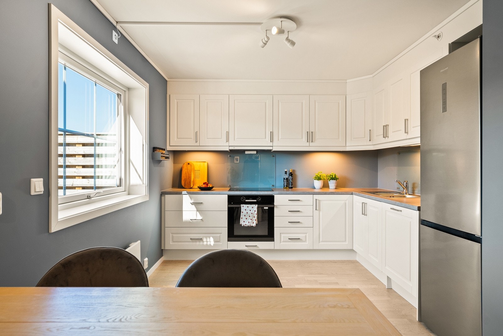 Kjøkkenet er oppført i en praktisk L-form. Kjøkkeninnredning med profilerte fronter. Laminat benkeplate med nedfelt kum i rustfritt stål. Induksjonstopp, stekeovn og oppvaskmaskin er integrert. Galleribilde