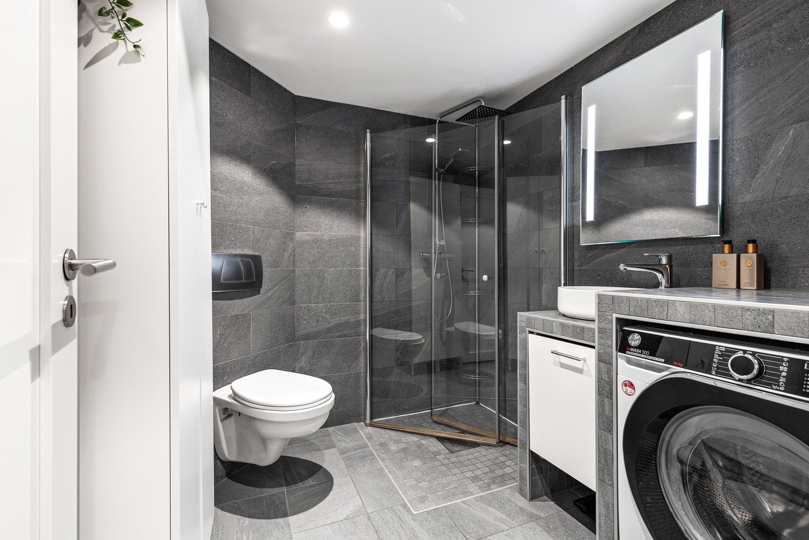 Rommet er utstyrt med vegghengt toalett samt dusjhjørne med regndusj og innfellbare dusjvegger Galleribilde