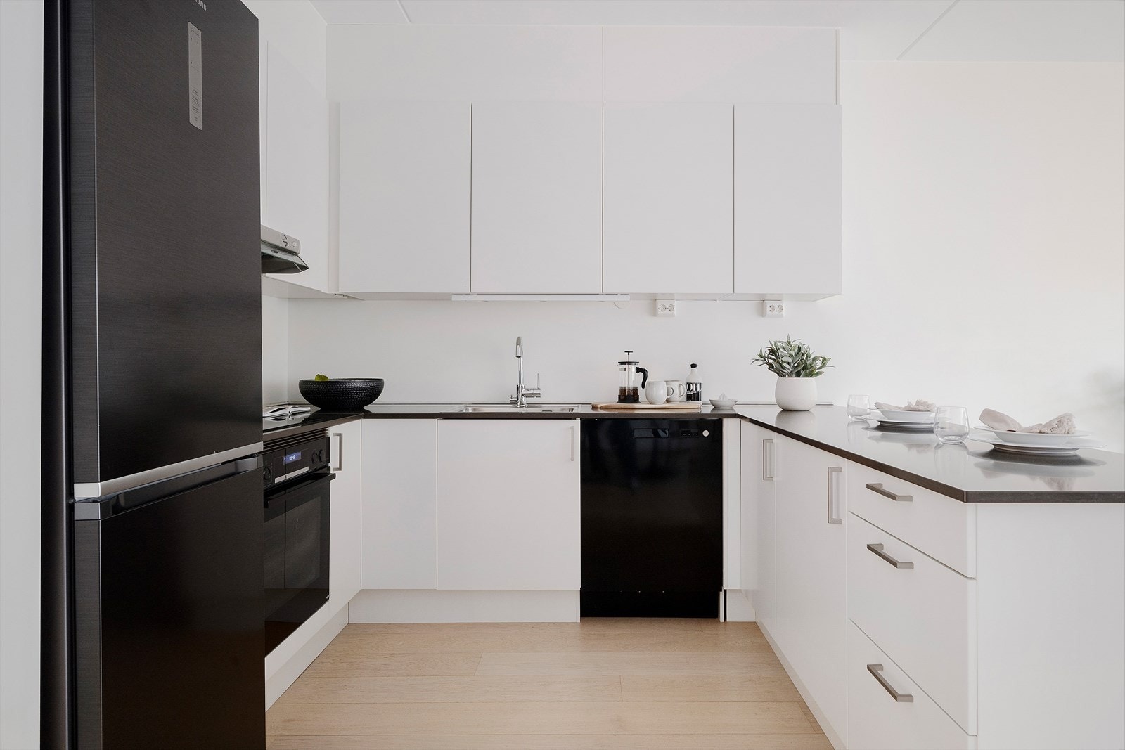 Moderne kjøkken fra byggeår med glatte fronter, påkostet benkeplate i kompositt og integrert komfyr og platetopp Galleribilde