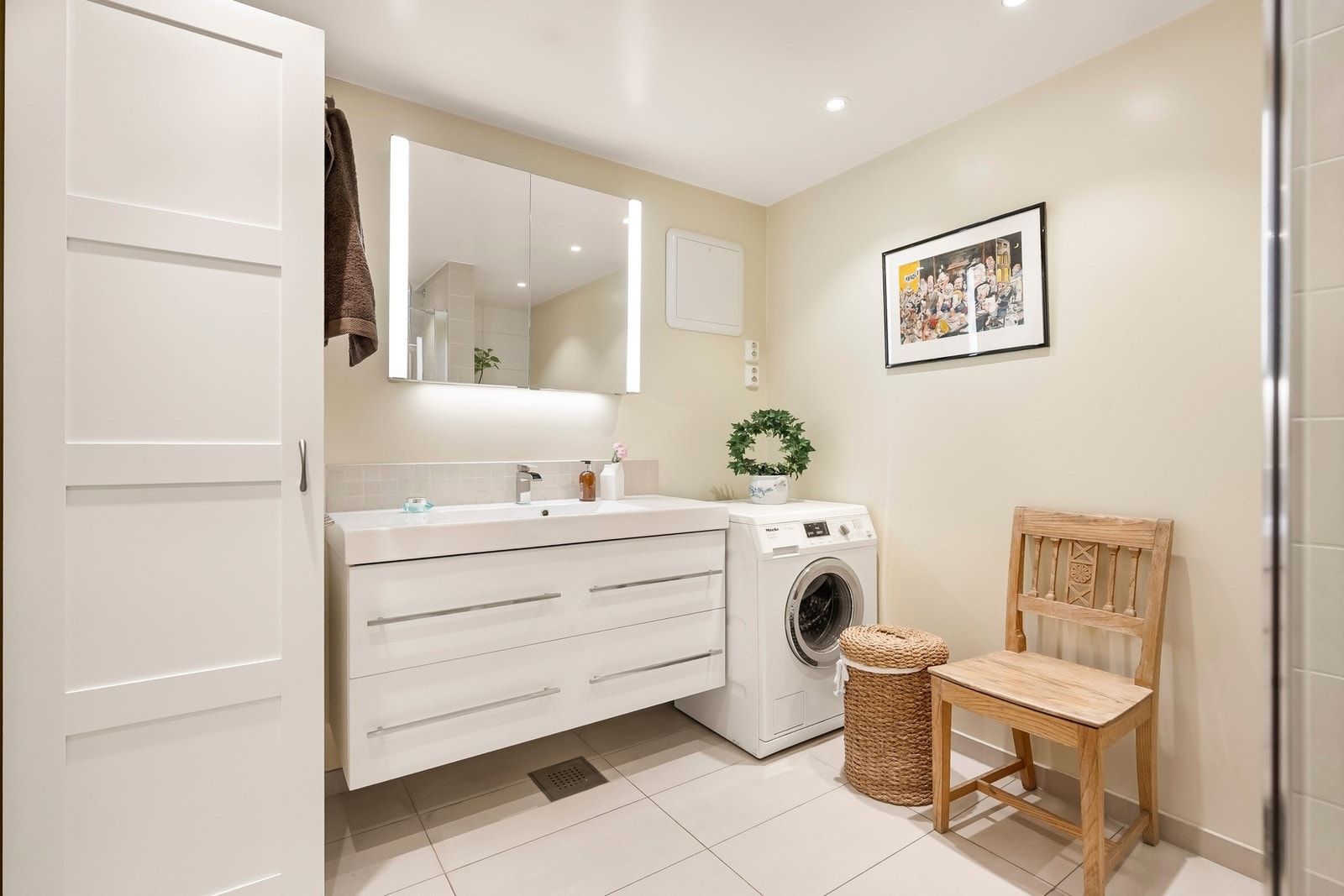 Badet har servantinnredning med skuffer og ovenpåliggende servant, samt speil med belysning på vegg over servant. Galleribilde