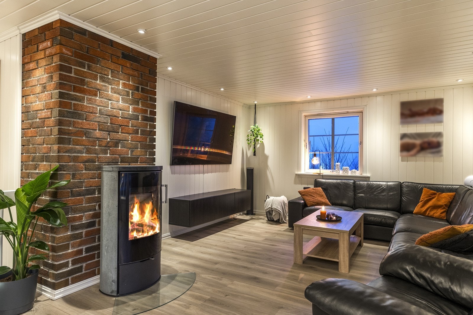En vedovn og en eksponert teglsteinsvegg skaper en lun atmosfære i stuen. Galleribilde