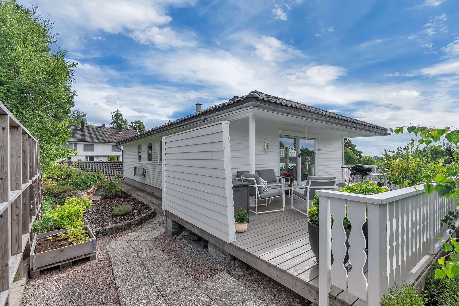 På baksiden av huset er det opparbeidet med blomsterbed og steinheller Galleribilde