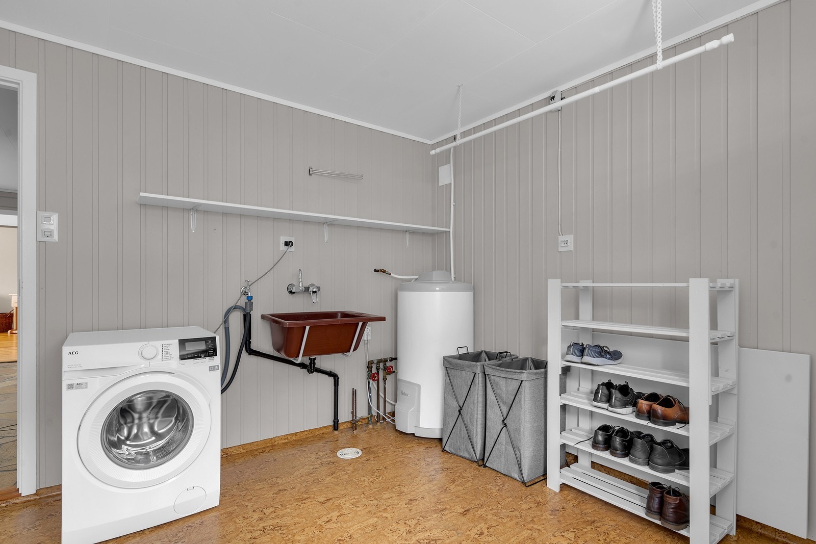 Stort vaskerom med utslagsvask, opplegg til vaskemaskin, varmtvannstank og varme i gulv Galleribilde